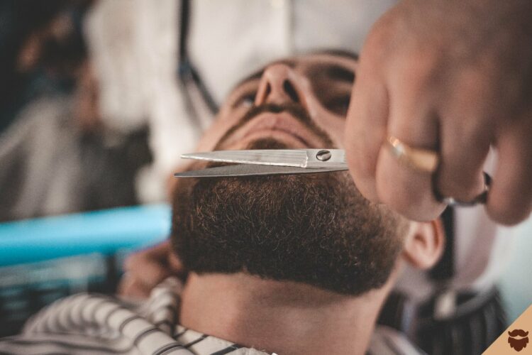 Hombre recortando su barba con tijeras