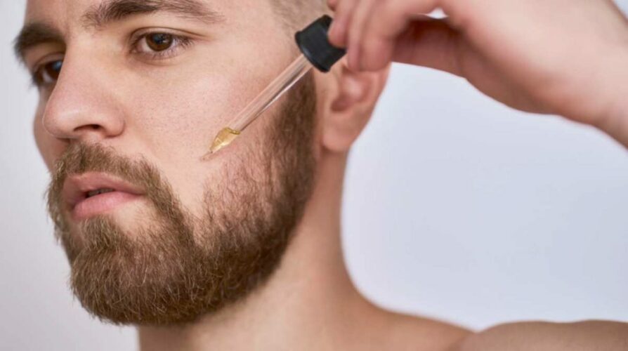 Homme avec pipette huile de jojoba barbe