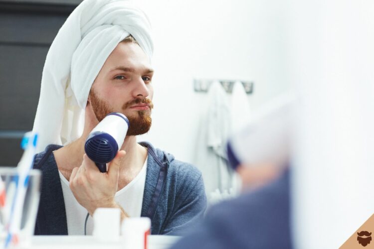 Homme qui se seche la barbe au seche cheveux