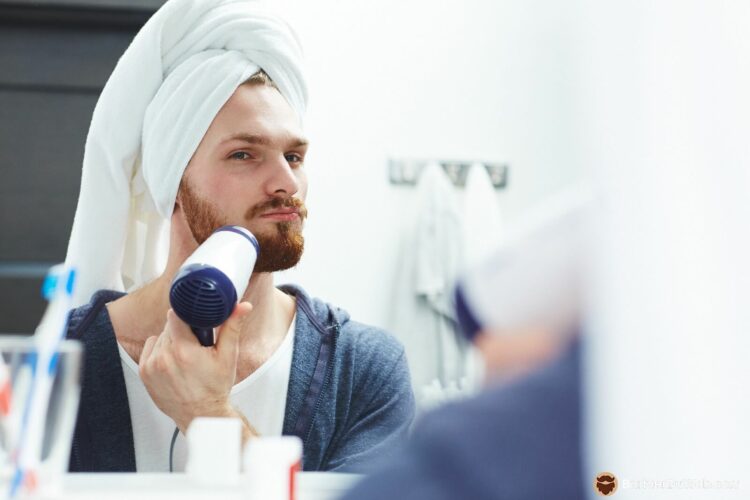 Man dries his beard with a hair dryer