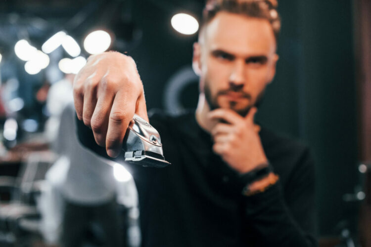 Bearded man holding a beard trimmer with vacuum system